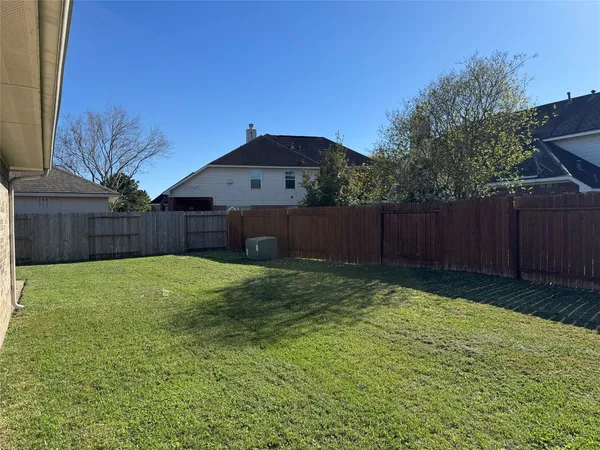 a view of a backyard with large trees and wooden fence