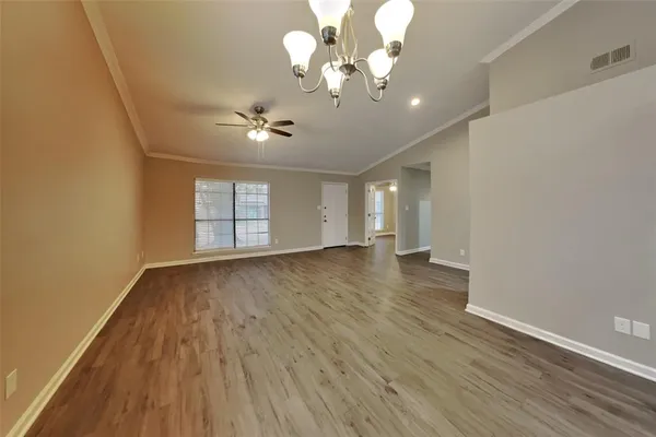 a view of an empty room with a window and wooden floor
