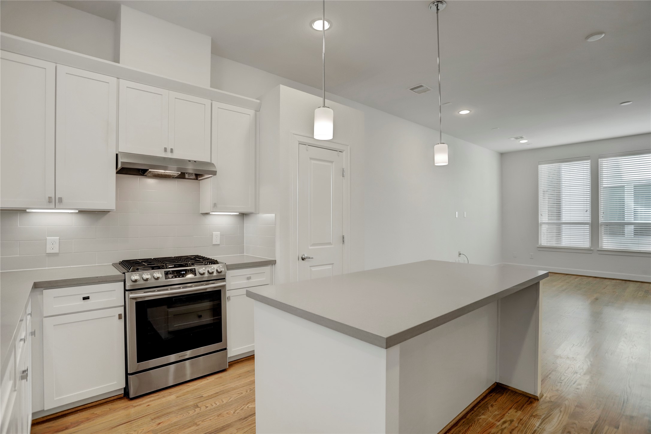 954 West 18th Street Houston, TX 77008 - Photo 4 of 30 The dazzling Chef's kitchen is the heart of the home, where you will find glossy white cabinetry with under-cabinet lighting, plus elegant quartz counters with a tile backsplash.