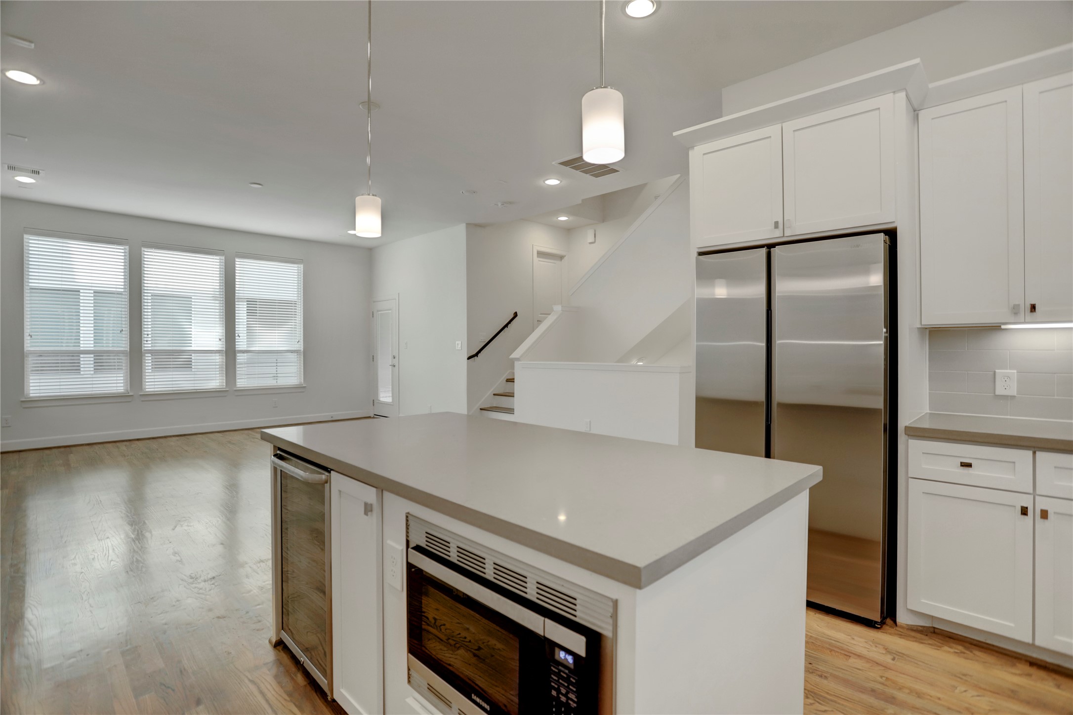 954 West 18th Street Houston, TX 77008 - Photo 6 of 30 The quartz-topped island with overhead pendant lighting stores the low-mounted microwave and wine fridge, while seconding as a breakfast bar on the opposite side. No expense was spared to make this kitchen both beautiful and functional!