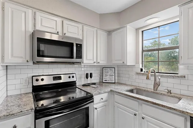 a kitchen with granite countertop a sink and steel appliances