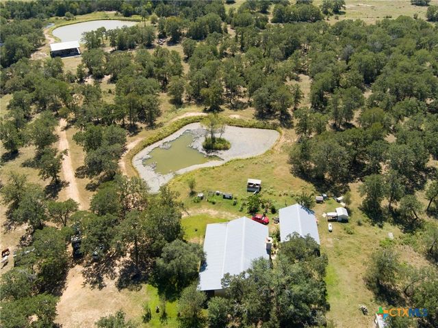 an aerial view of residential house with outdoor space and trees all around