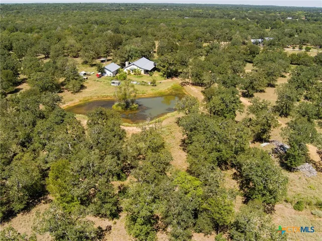 an aerial view of residential houses with outdoor space and trees