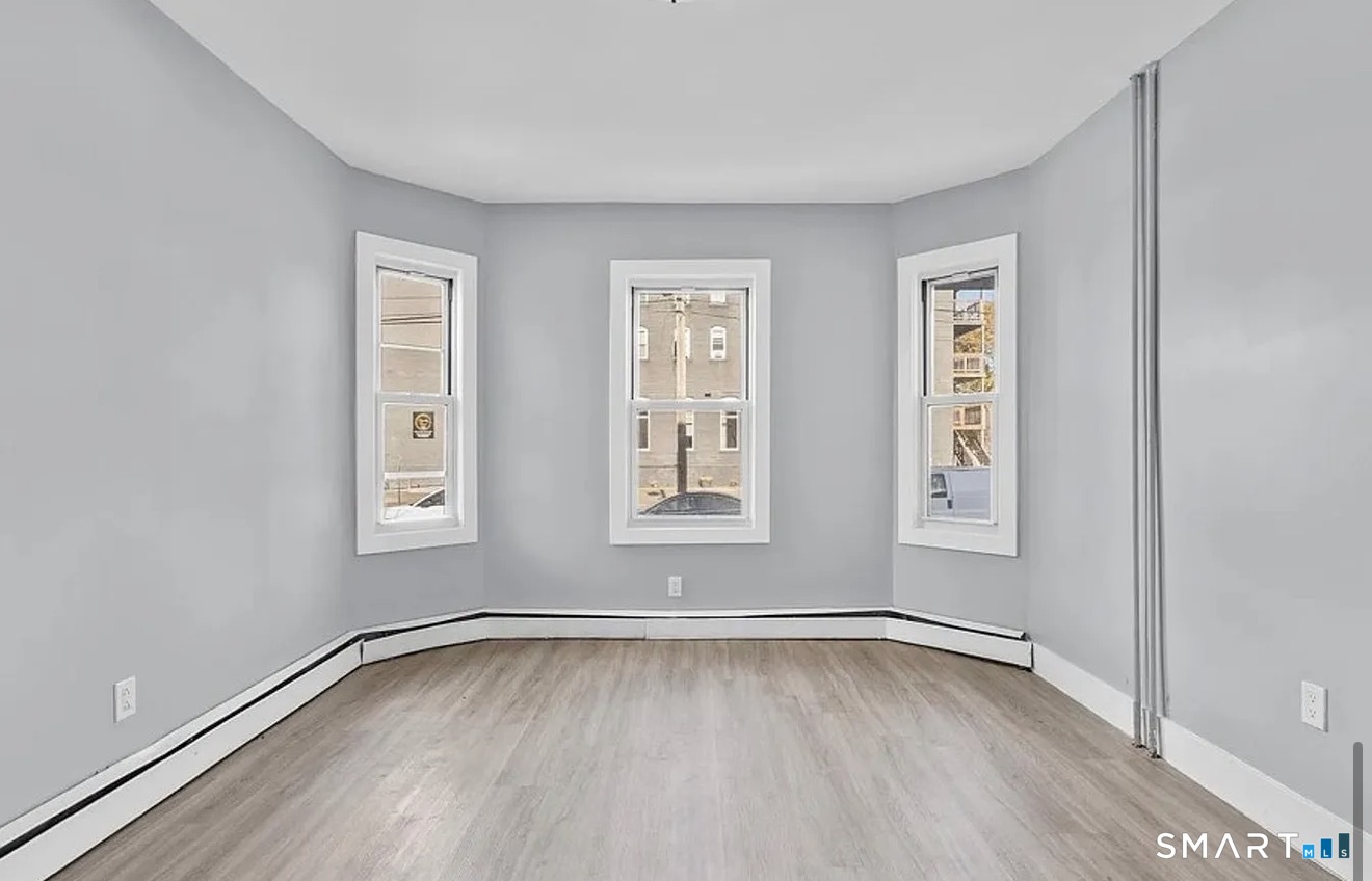 748 Maple Street, Unit 3 Bridgeport, CT 06608 - Photo 6 of 13 a view of an empty room with wooden floor and a window