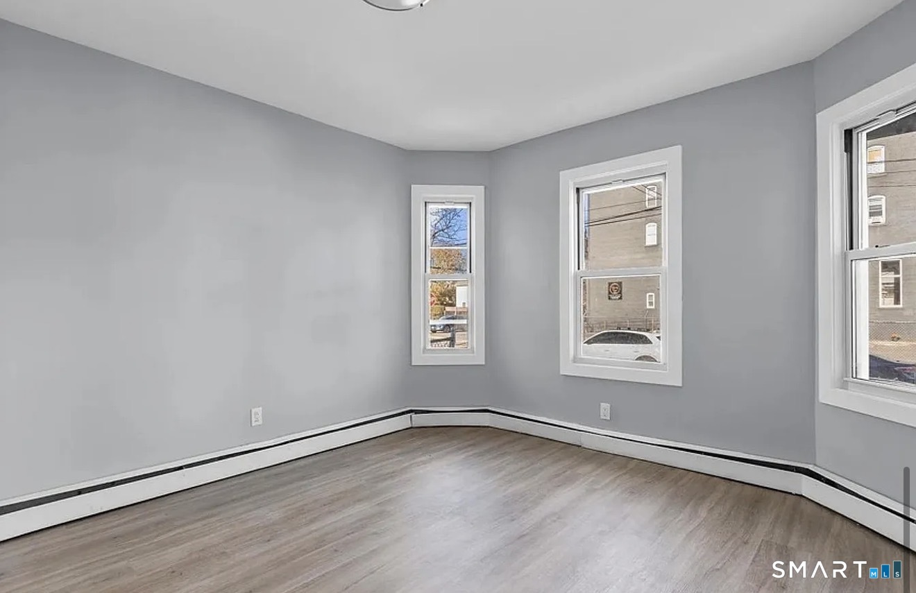 748 Maple Street, Unit 3 Bridgeport, CT 06608 - Photo 7 of 13 an empty room with wooden floor and windows