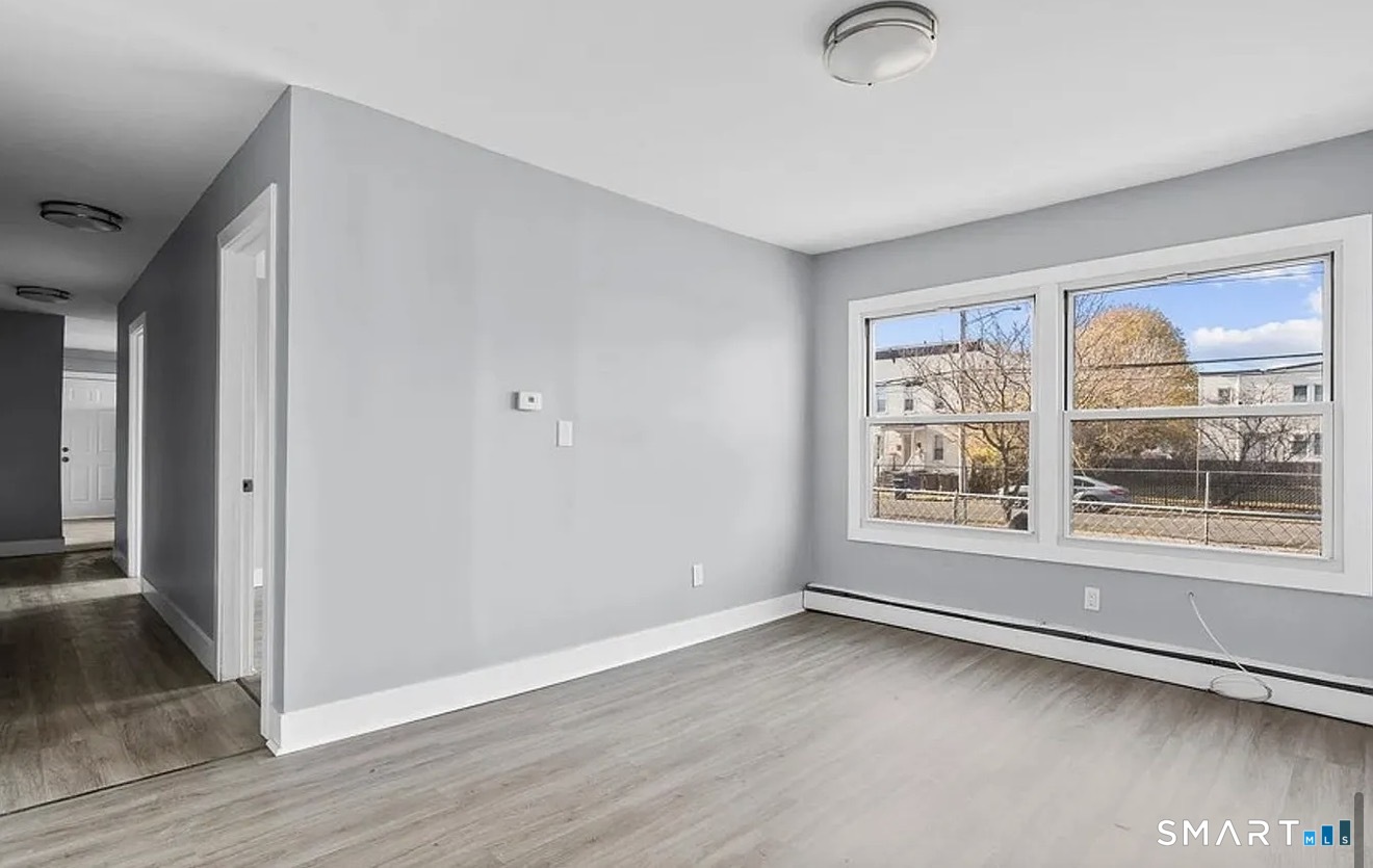 748 Maple Street, Unit 3 Bridgeport, CT 06608 - Photo 8 of 13 an empty room with wooden floor and windows
