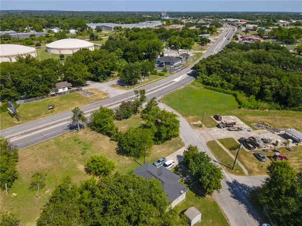 an aerial view of a residential houses with outdoor space and trees all around