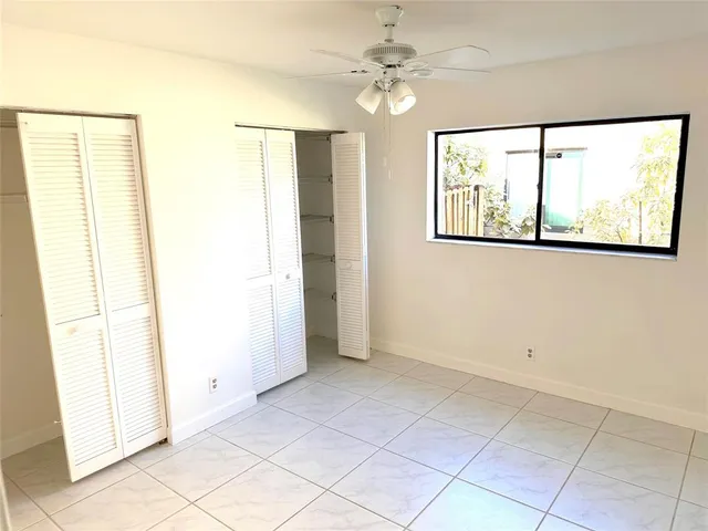 an empty room with windows and fan