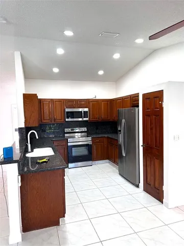 a kitchen with stainless steel appliances kitchen island granite countertop a refrigerator and a sink