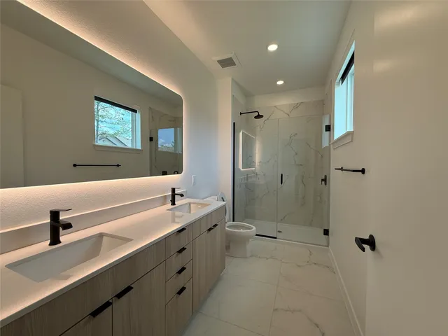 a bathroom with a double vanity sink mirror and shower