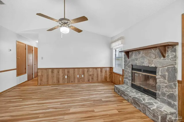 a view of wooden floor a fireplace and a chandelier fan in living room