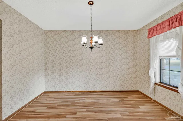 a view of a room with wooden floor chandelier and windows