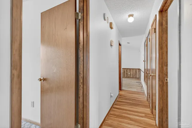 a view of a hallway with a wooden door and stairs
