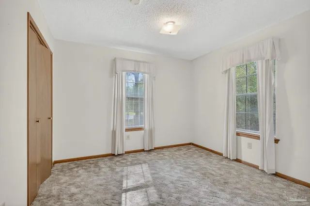 a view of an empty room with window and closet area
