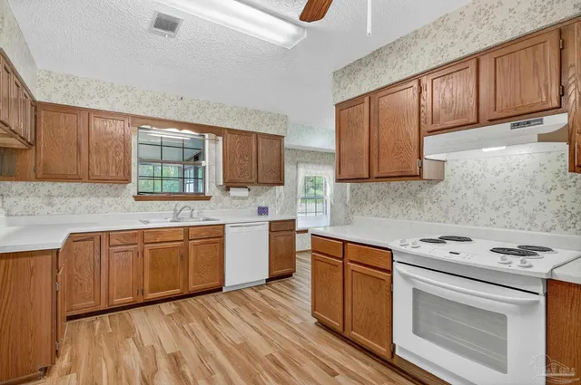 a kitchen with stainless steel appliances granite countertop wooden cabinets a stove a sink and dishwasher with wooden floor