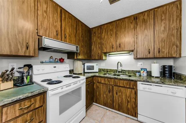 a kitchen with stainless steel appliances granite countertop wooden cabinets sink stove and refrigerator