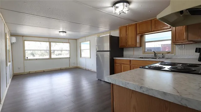 a kitchen with granite countertop a stove a sink dishwasher a refrigerator and wooden floor