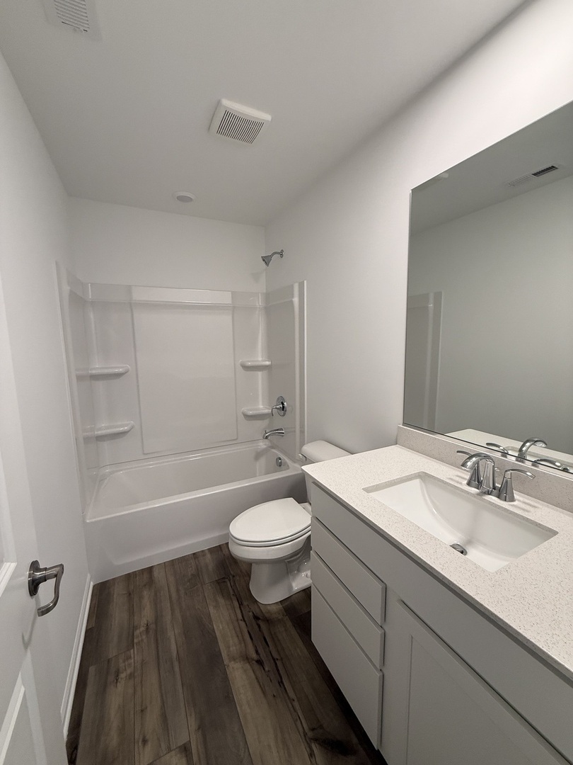 10232 McMahon Way, Unit 10232 Huntley, IL 60142 - Photo 20 of 22 a bathroom with a sink a toilet a mirror and bathtub