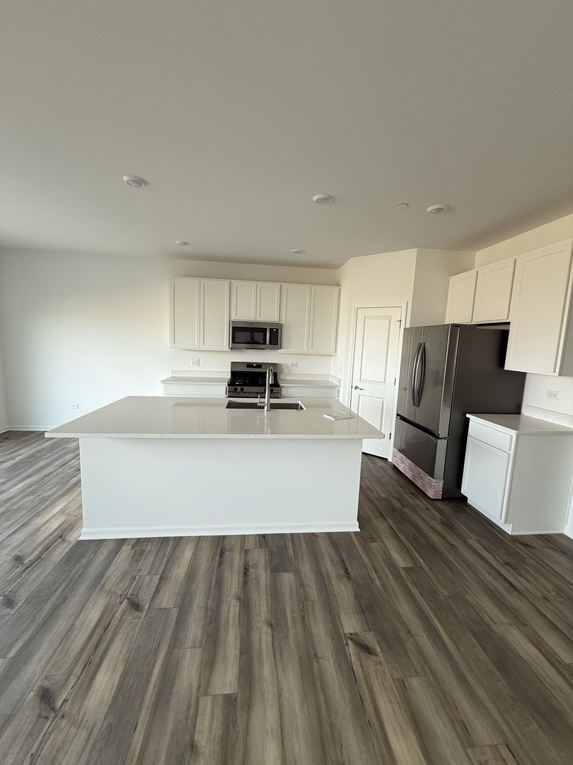 10232 McMahon Way, Unit 10232 Huntley, IL 60142 - Photo 7 of 22 a large kitchen with wooden floor and stainless steel appliances