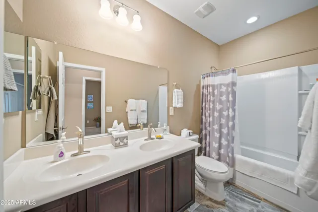 a bathroom with a double vanity sink toilet mirror and shower