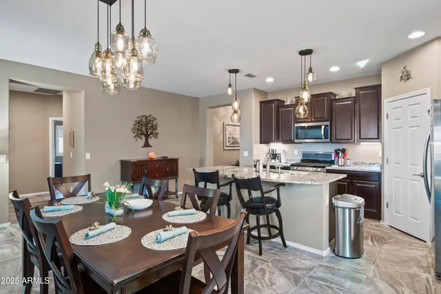 a open dining room with stainless steel appliances kitchen island a table and chairs