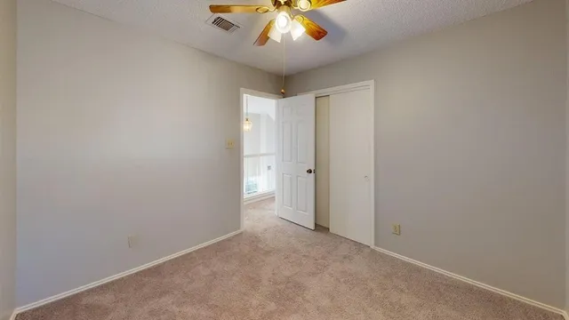 an empty room with chandelier fan and windows