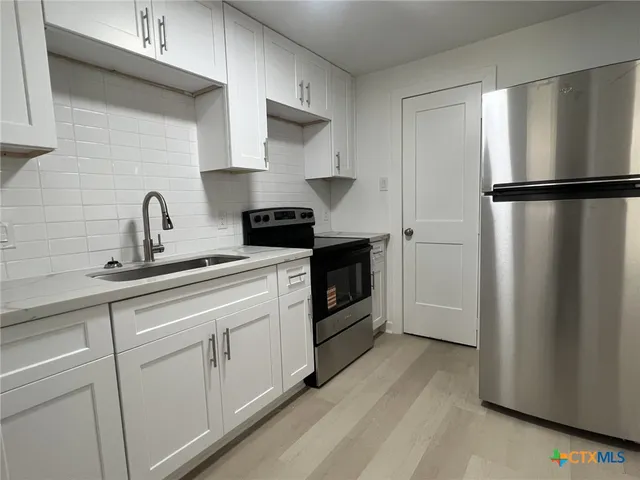 a kitchen with stainless steel appliances a refrigerator sink and cabinets