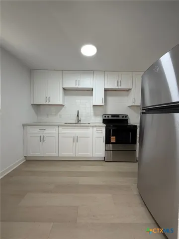 a kitchen with white cabinets and stainless steel appliances