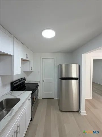 a kitchen with a refrigerator sink and cabinets