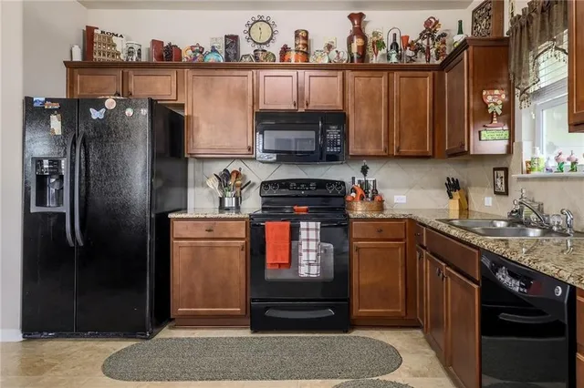 a kitchen with stainless steel appliances granite countertop a refrigerator a stove and a sink