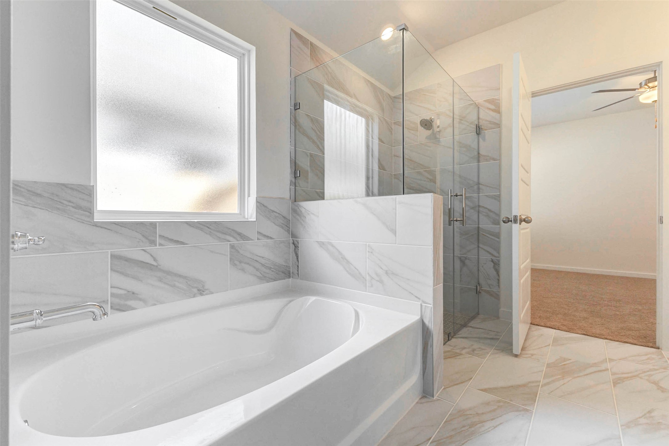 6463 Escondido Drive Rosharon, TX 77583 - Photo 22 of 30 Primary bath featuring a soaking tub, separate glass-enclosed shower, marble-look tile surround, and natural light from the privacy window. The layout creates a bright and relaxing retreat with clean modern finishes.