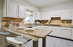 a kitchen with stainless steel appliances granite countertop a sink a stove and white cabinets