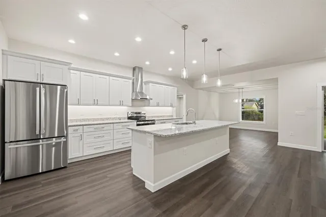 a kitchen with kitchen island a sink stainless steel appliances and wooden floor