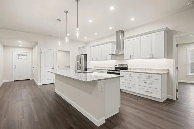 a kitchen with white cabinets stainless steel appliances and wooden floor