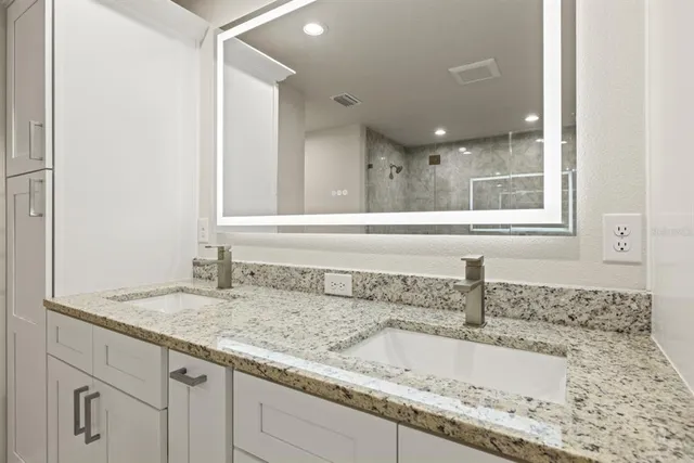 a bathroom with a granite countertop sink and a mirror
