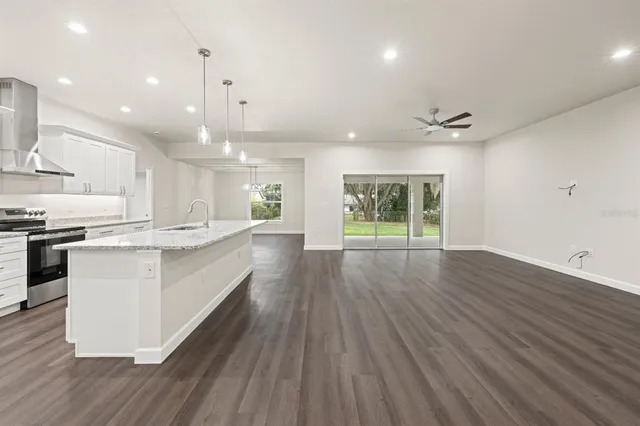 a large kitchen with stainless steel appliances kitchen island a large counter top and a wooden floors