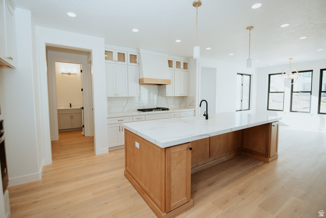 1378 North 1500 West, Unit 8 Mapleton, UT 84664 - Photo 5 of 20 Spacious kitchen featuring a large central island with a light wood base and white countertop, white perimeter cabinetry with upper glass-front cabinets, a built-in gas range, and wood-finish flooring