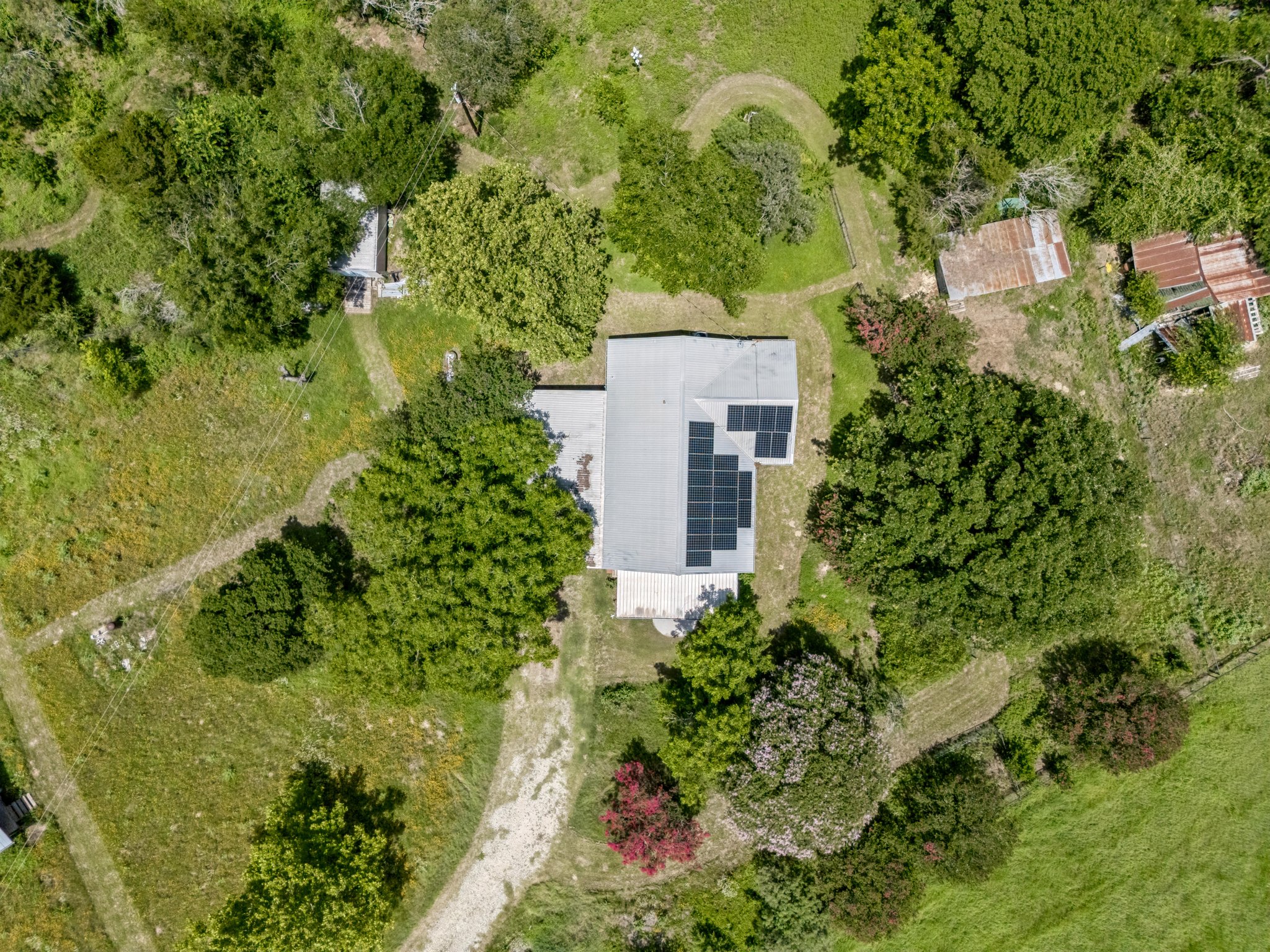 2089 Farm To Market Road 1704 Elgin, TX 78621 - Photo 29 of 31 Perched amidst lush greenery, this property features a home equipped with modern solar panels.