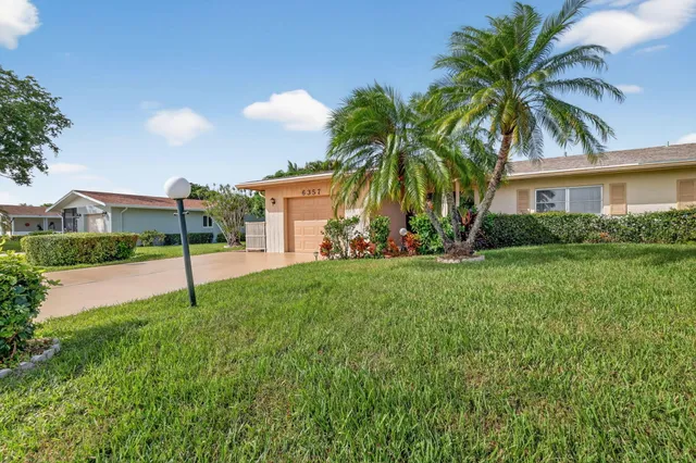 a view of a house with a big yard and palm trees