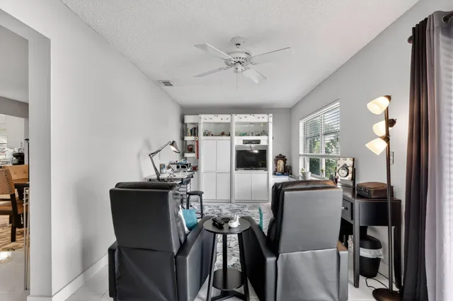 a kitchen with granite countertop white cabinets a sink a stove a dining table and chairs