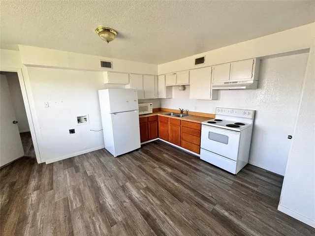 a kitchen with wooden floors and white appliances