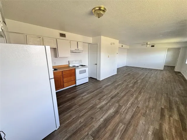 a kitchen with granite countertop a refrigerator stove and sink