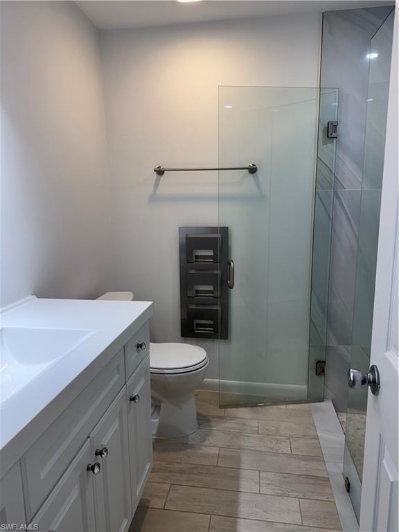 156 Harrison Road, Unit J4 Naples, FL 34112 - Photo 21 of 29 Full bathroom with toilet, a shower stall, wood finish floors, and vanity
