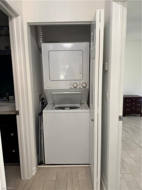 156 Harrison Road, Unit J4 Naples, FL 34112 - Photo 23 of 29 Clothes washing area with stacked washer and dryer, wood tiled floor, and a sink