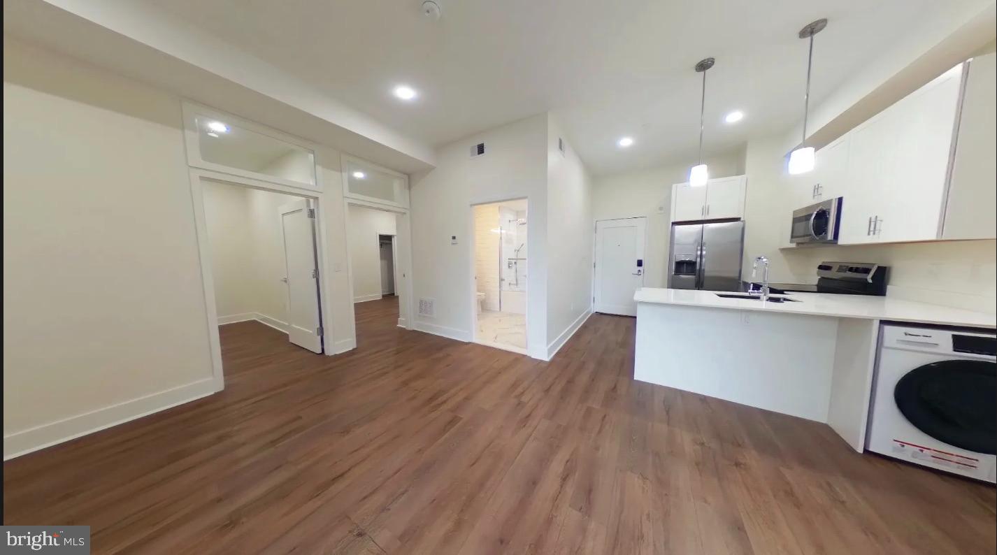 150 South Independence Mall West, Unit 802 Philadelphia, PA 19106 - Photo 3 of 9 a open kitchen with white cabinets stainless steel appliances and wooden floor