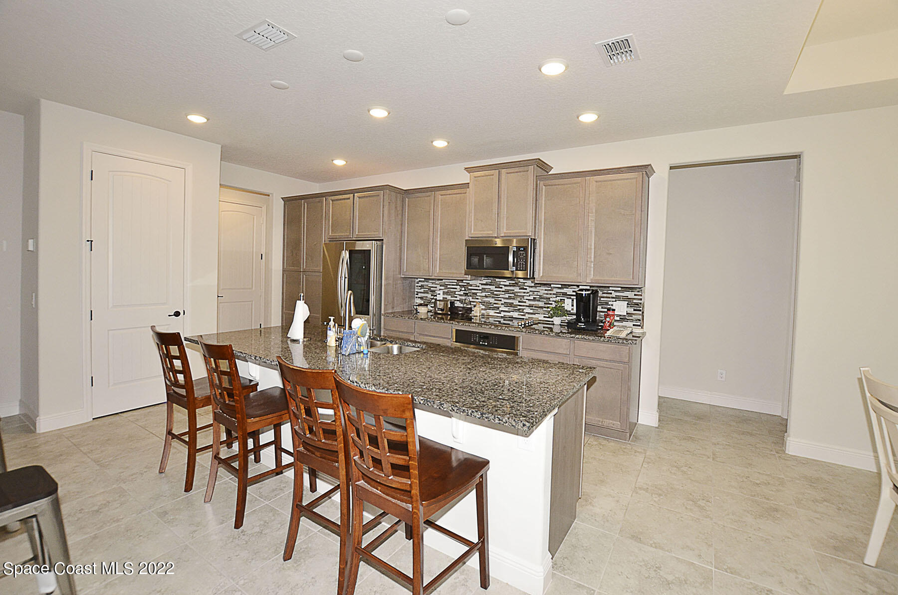 1923 Killian Drive Palm Bay, FL 32905 - Photo 18 of 44 a kitchen with stainless steel appliances granite countertop a stove a sink a dining table and chairs