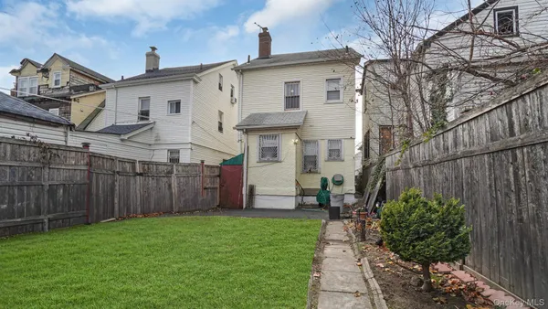 a view of a white house next to a yard with wooden fence
