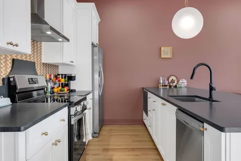 a kitchen with stainless steel appliances granite countertop a sink a stove white cabinets and a granite counter tops