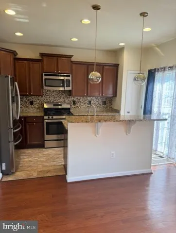 a kitchen with stainless steel appliances granite countertop a stove a refrigerator a sink and a microwave