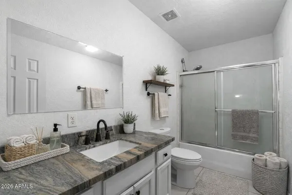 a bathroom with a granite countertop sink a toilet and shower